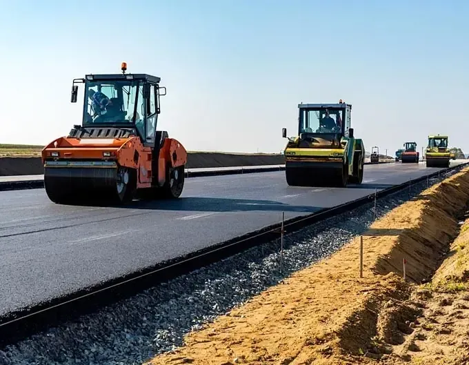 Roller compactors paving a road as part of Kaplan Industry equipment fleet